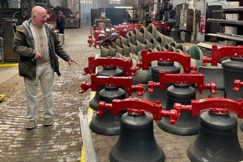 Taylor's Bell Foundry Tour. John pointing at a set of bells that have newly painted Headstocks. 